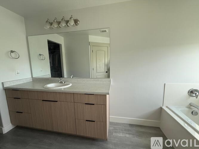 A bathroom with a sink, mirror, and bathtub.