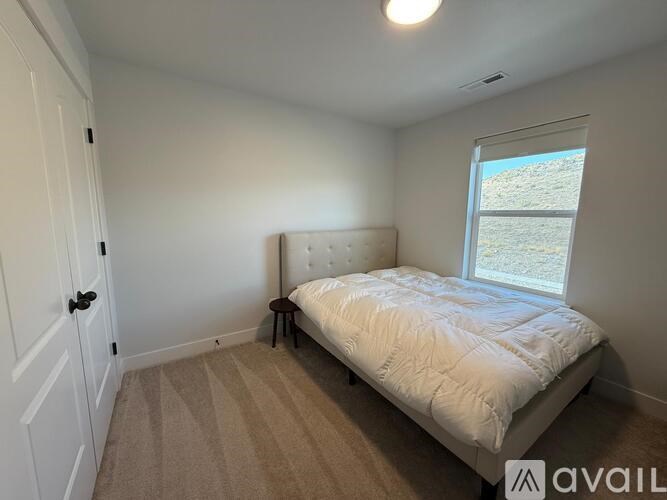 A bedroom with a bed, carpet, and a window.