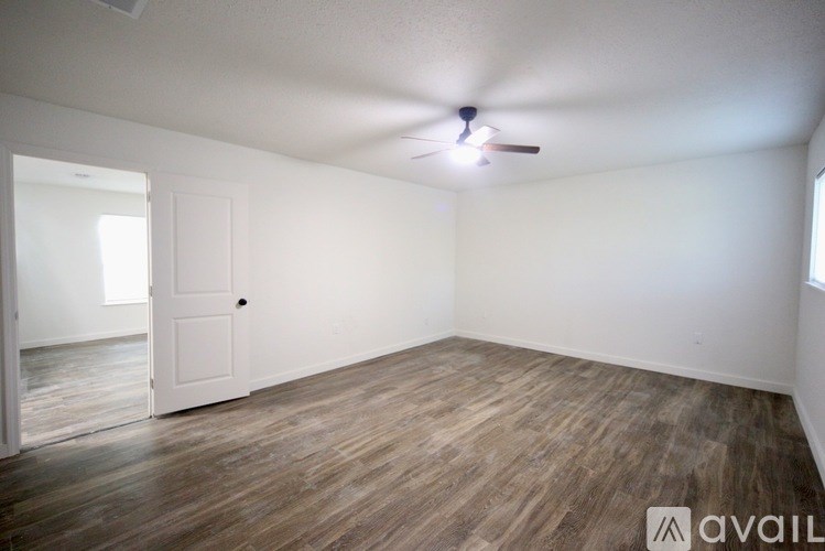A room with a door, window, and wooden floor.