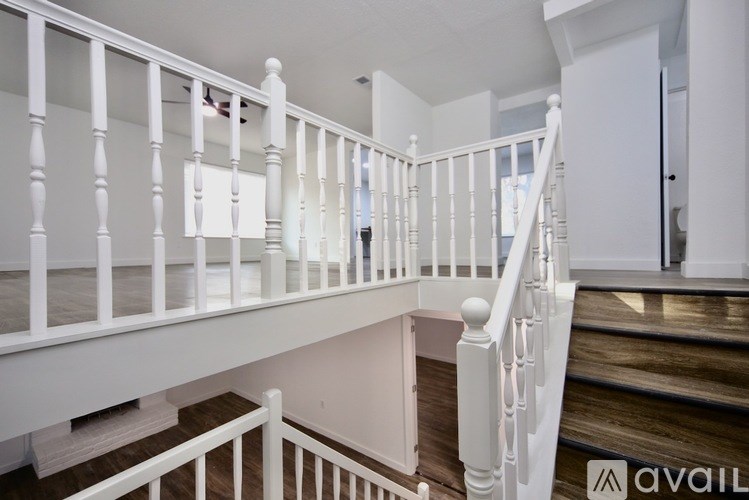 A kitchen with a black fridge, wooden countertops, and white cabinets.