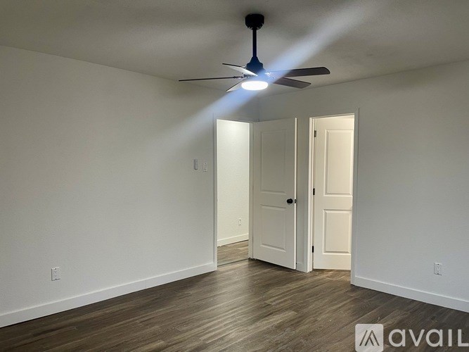 A room with a ceiling fan and wooden flooring.
