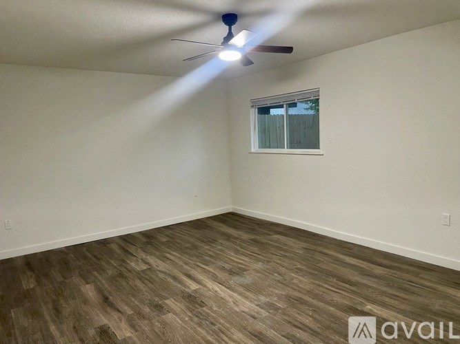A room with a ceiling fan and a window with blinds.