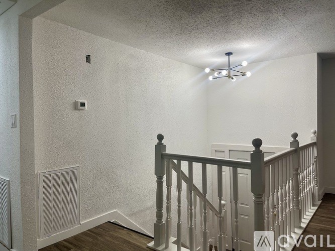A white room with a staircase and a light fixture.