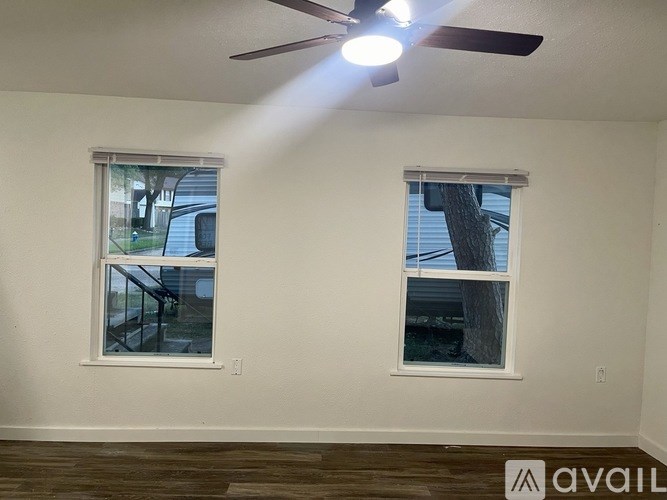 A room with two windows and a ceiling fan.
