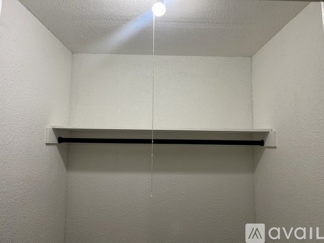 A white wall with a shelf and a light hanging from the ceiling.
