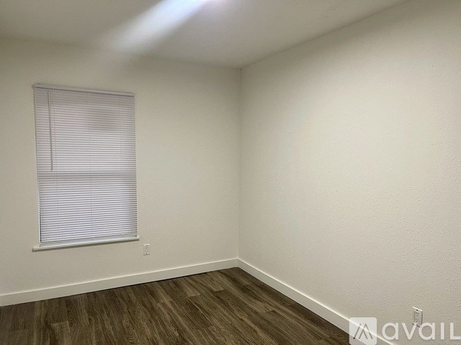 A room with wooden flooring and a window with blinds.