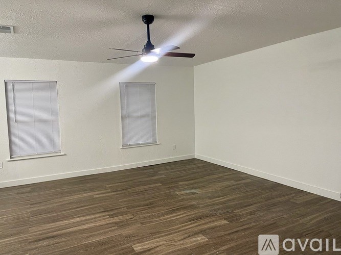 A room with a ceiling fan and two windows.