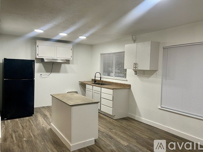 A kitchen with a black fridge, white cabinets, and a wooden island.
