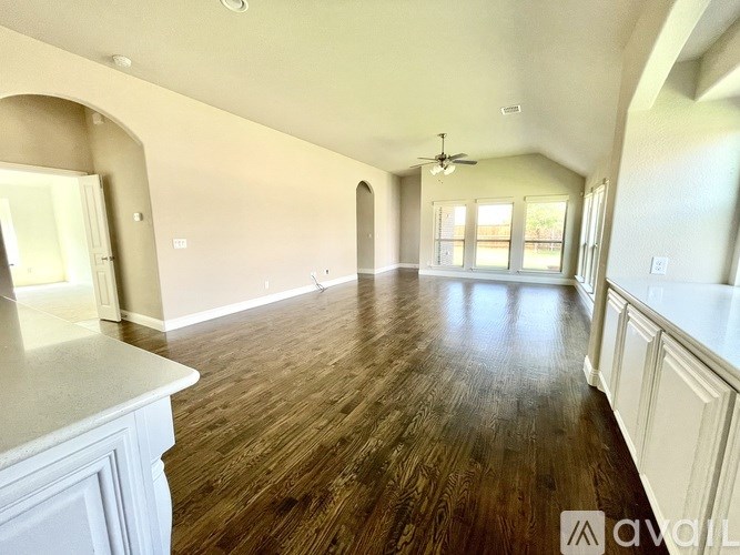 A spacious room with wooden floors and white walls.