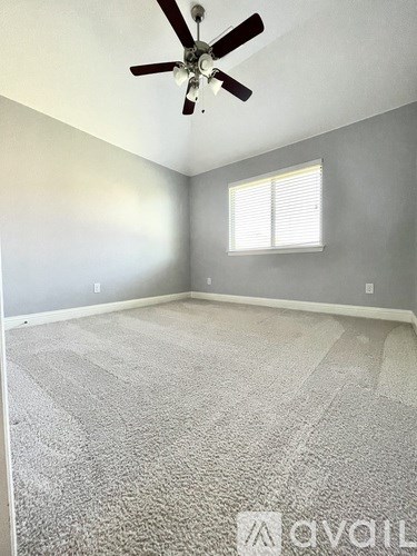 A room with a ceiling fan and a window with blinds.