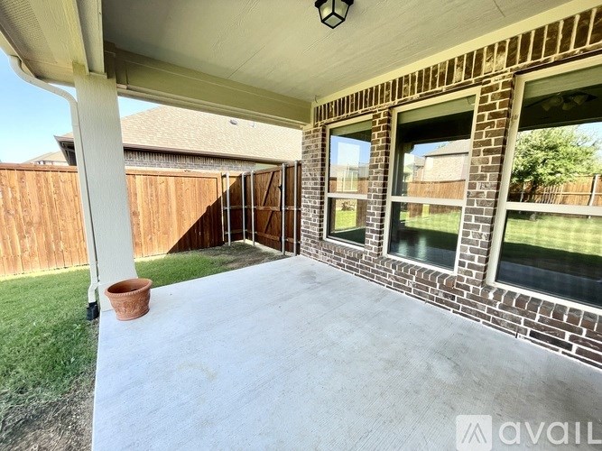 A patio with a white floor and a brick wall with windows.