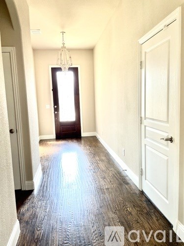 A hallway with a chandelier and a door at the end.