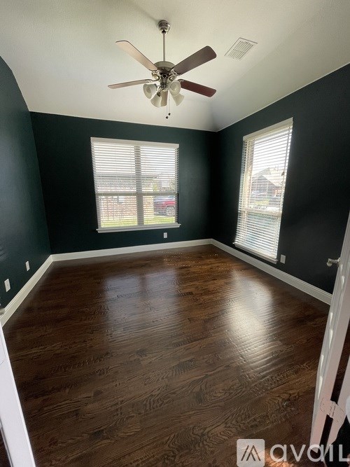 A room with a ceiling fan and wooden flooring.