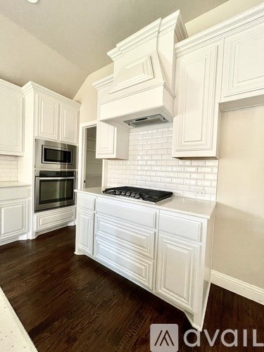 A kitchen with white cabinets and a black stove top.