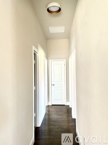 A long hallway with a white door at the end.