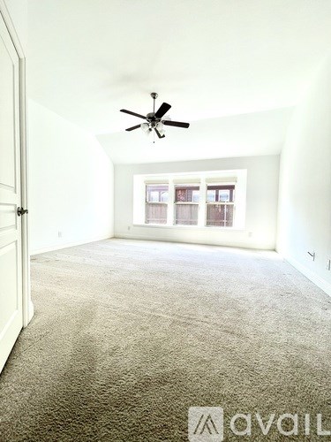 A carpeted room with a ceiling fan and a window.