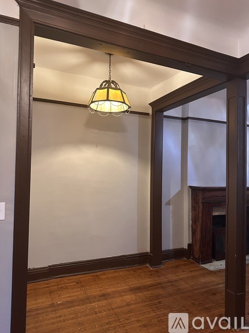 A room with a wooden floor and a hanging light fixture.