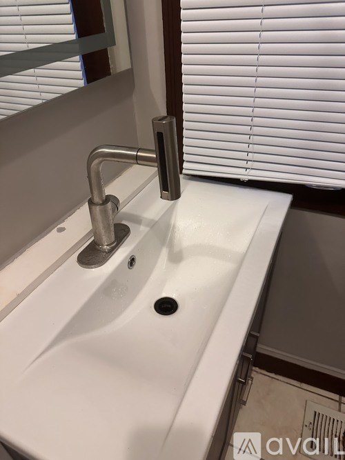 A white sink with a chrome faucet and a mirror above it.