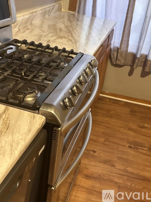 A stainless steel gas stove with a white countertop.