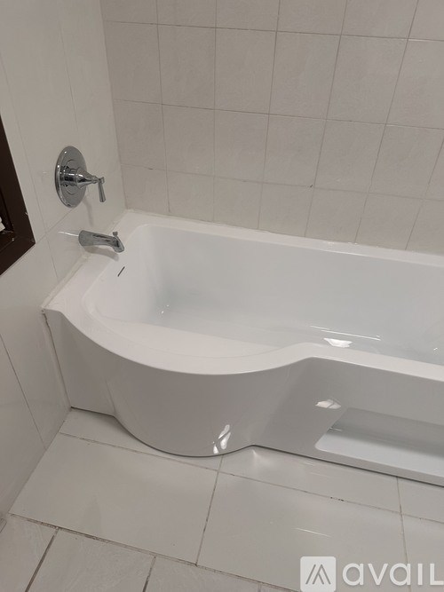 A white bathtub with a silver faucet and shower head in a bathroom.