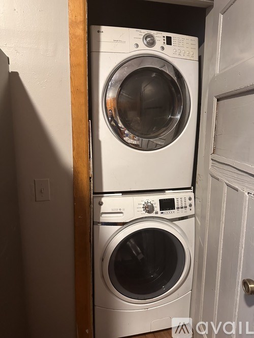 Two white front load washing machines stacked on top of each other in a small room.