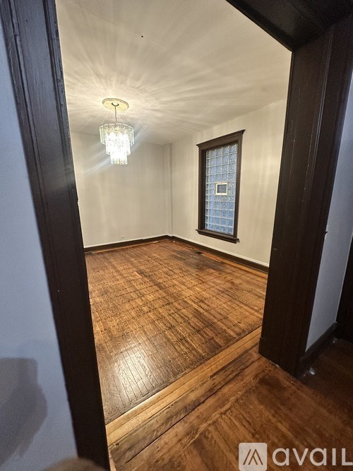 A room with wooden floors and a chandelier hanging from the ceiling.