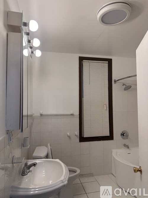 A white sink in a bathroom with a mirror and lights above it.