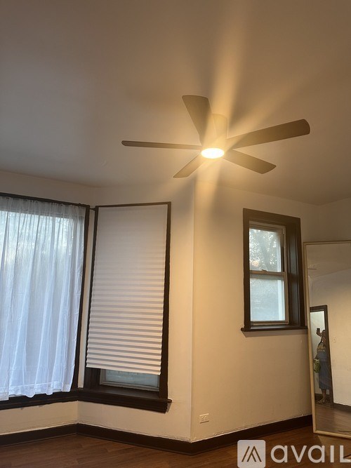 A room with a window and a fan on the ceiling.