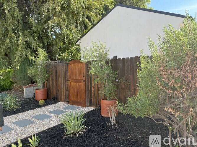 A white house with a brown fence and a garden in front.