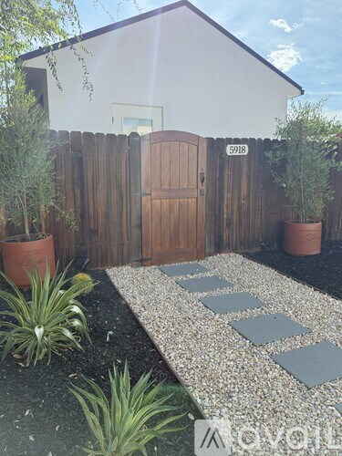 A white house with a brown door and a wooden fence.