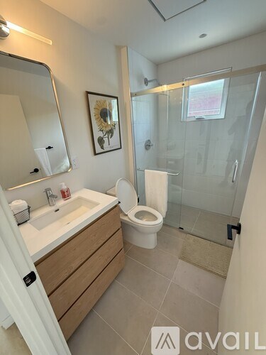 A bathroom with a toilet, sink, mirror, and shower.