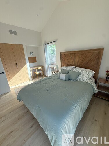 A bedroom with a bed, nightstand, and a window.