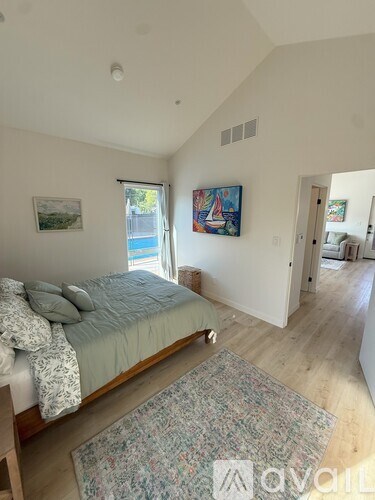 A bedroom with a bed, a rug, and a painting on the wall.