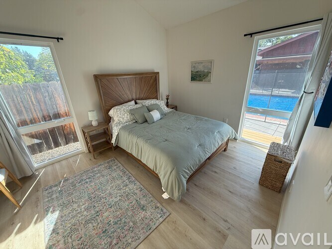 A bedroom with a large bed and a view of a pool through a sliding glass door.