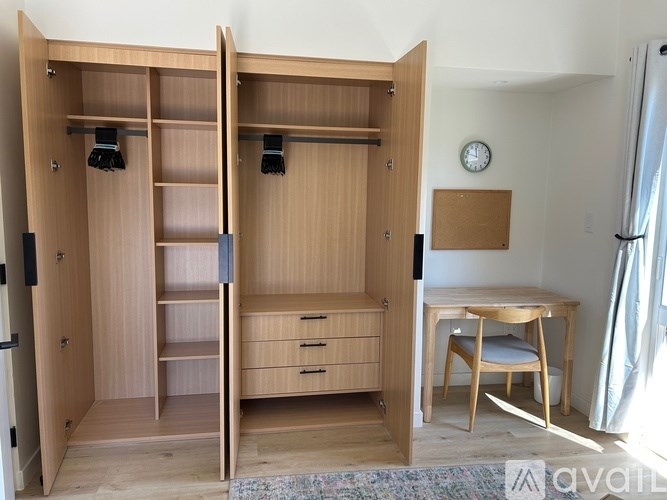 A room with a wardrobe, desk, and chair.