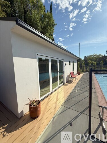 A white house with a wooden deck and a potted plant.