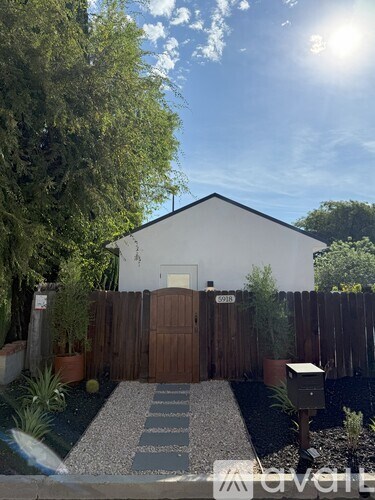 A white house with a brown fence and a mailbox.