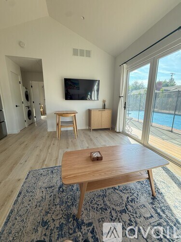 A living room with a television, a wooden table, and a rug.