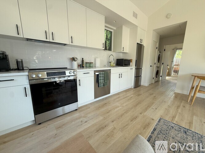 A kitchen with white cabinets and a wooden floor.