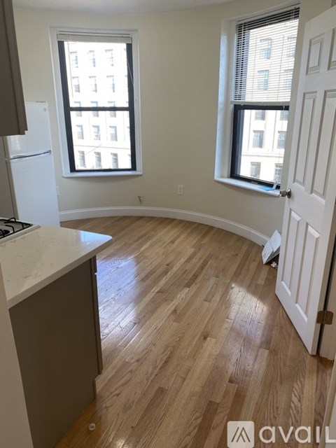 A kitchen with a refrigerator and a wooden floor.