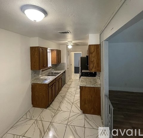 A kitchen with brown cabinets and a marble countertop.