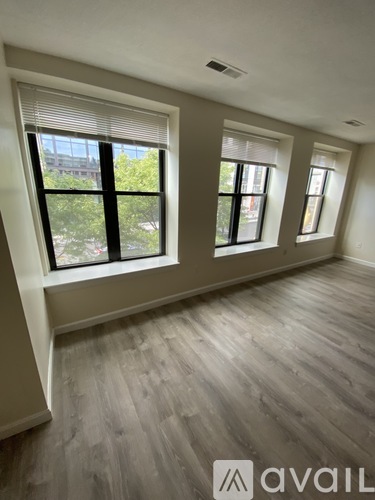A room with wooden flooring and three windows.