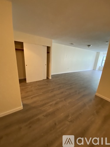 A room with wooden flooring and white walls, with a logo that reads "avaiL" in the bottom right corner.