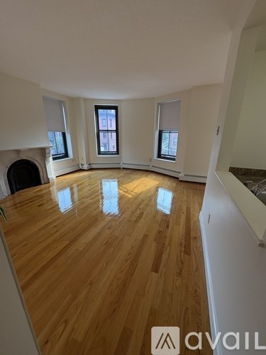 A room with wooden flooring and three windows.