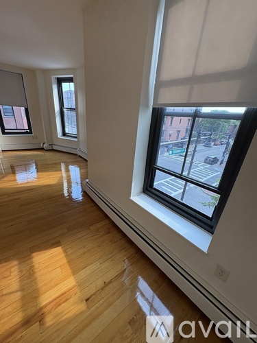 A room with wooden floors and three windows.