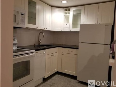 A kitchen with white cabinets and a black countertop.