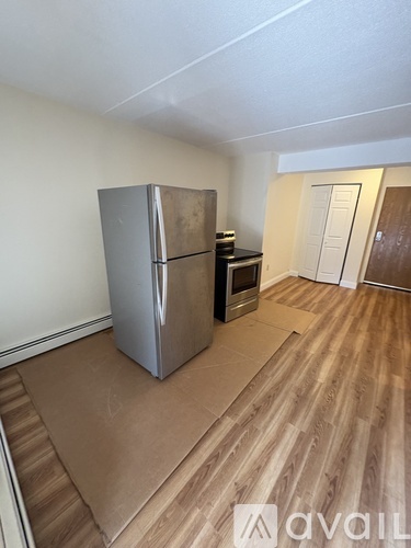 A kitchen area with a stainless steel refrigerator and wooden flooring.