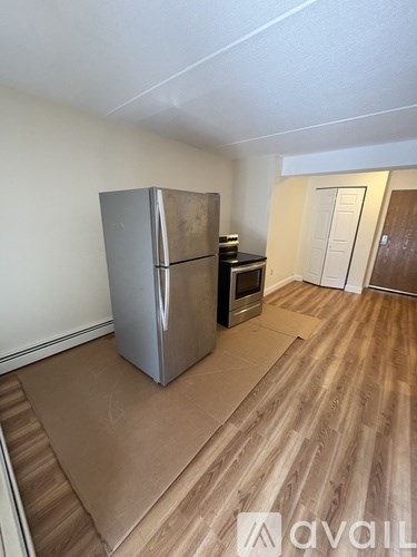 A kitchen area with a stainless steel refrigerator and wooden flooring.