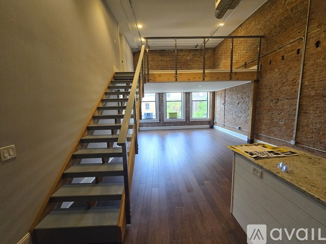 A long staircase with wooden steps and railings leads to a bright room with a window.