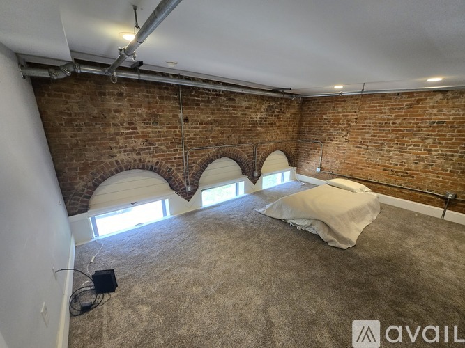 A room with a brick wall and a bed with a white cover.